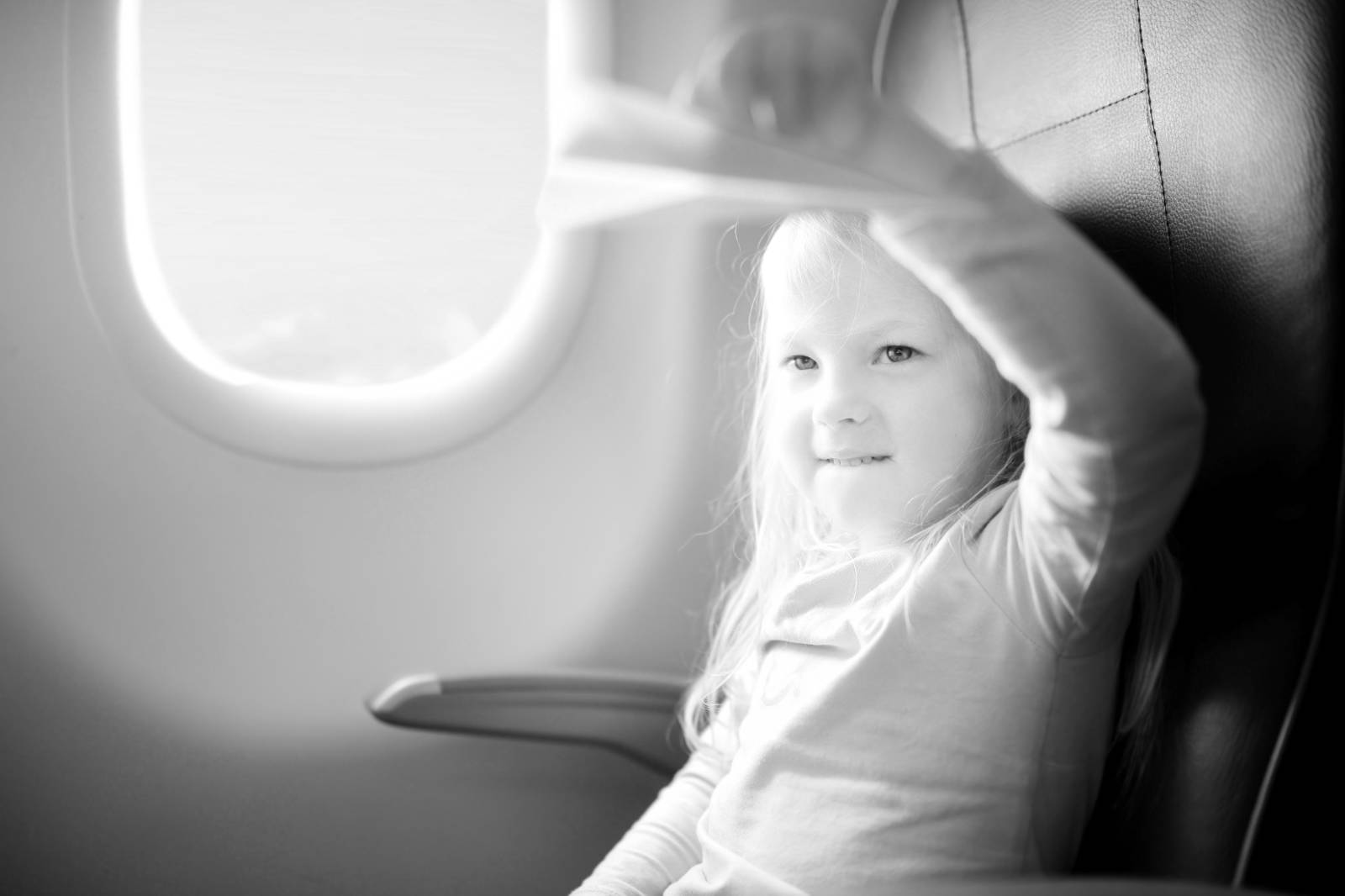 Una bambina che saluta dal finestrino di un aereo